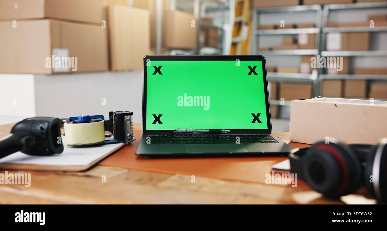 Distribuzione, schermo verde e laptop in deposito per sito web, postazione di lavoro o registro logistico alla scrivania. Espositore tecnico, spazio di mockup o tazza in magazzino Foto Stock