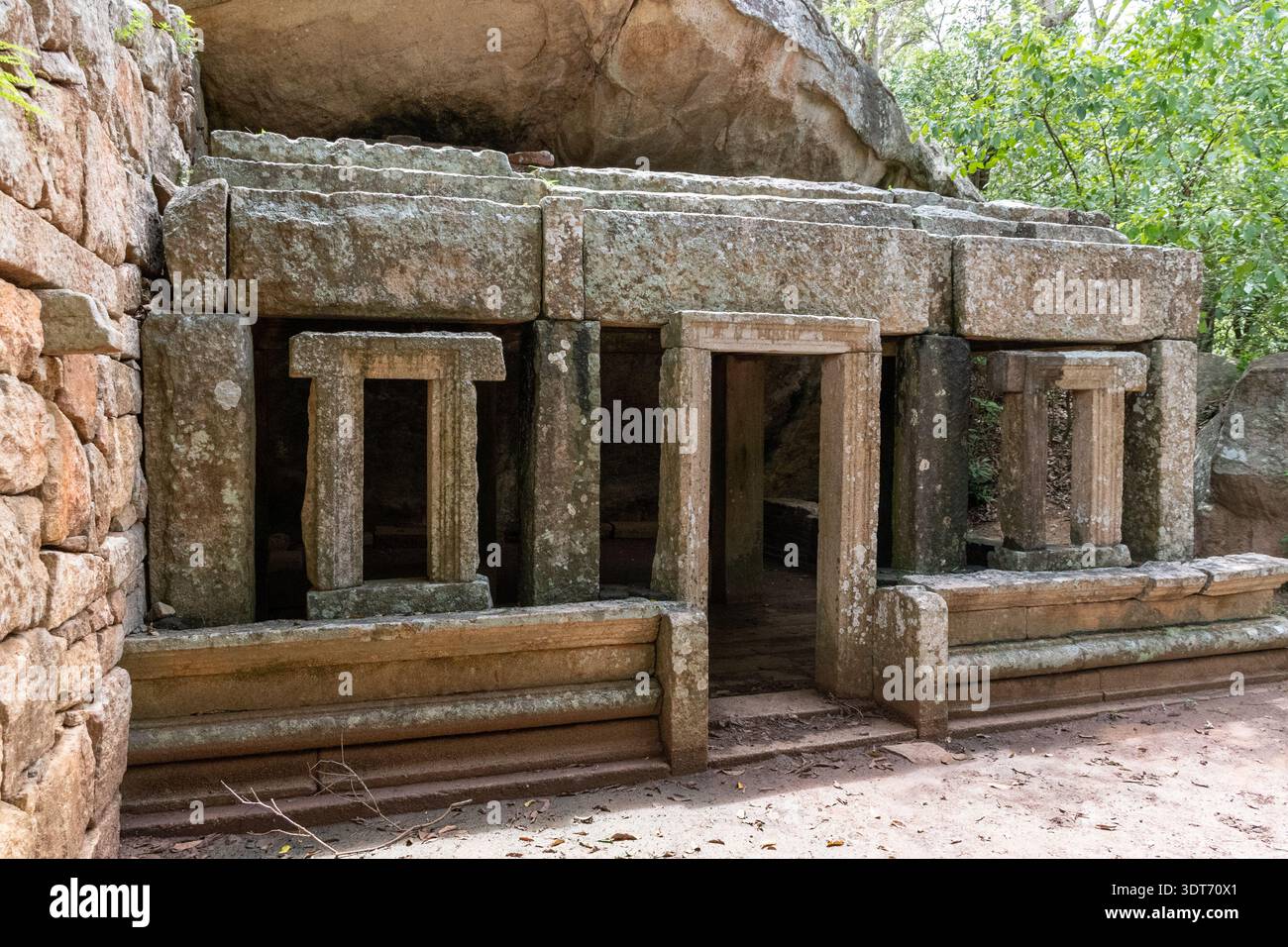 Uno scatto orizzontale a livello degli occhi cattura le antiche rovine di pietra di un monastero buddista a Kaludiya Pokuna, Mihintale, Sri Lanka. Foto Stock