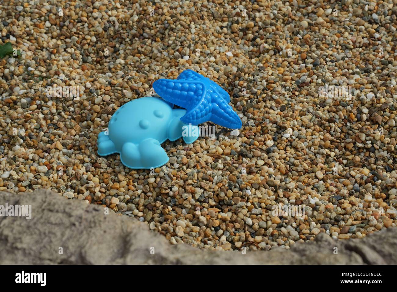 Creature marine giocattolo da spiaggia sulla spiaggia di ciottoli che simboleggiano il turismo responsabile il localismo di microavventura un'infanzia sostenibile gioca a biopfilia vita lenta Foto Stock