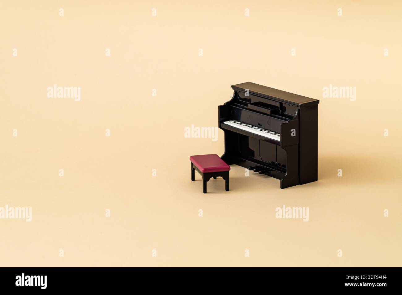 Mini pianoforte verticale con panca su sfondo beige. Concetto musicale minimalista con spazio di copia. Foto Stock