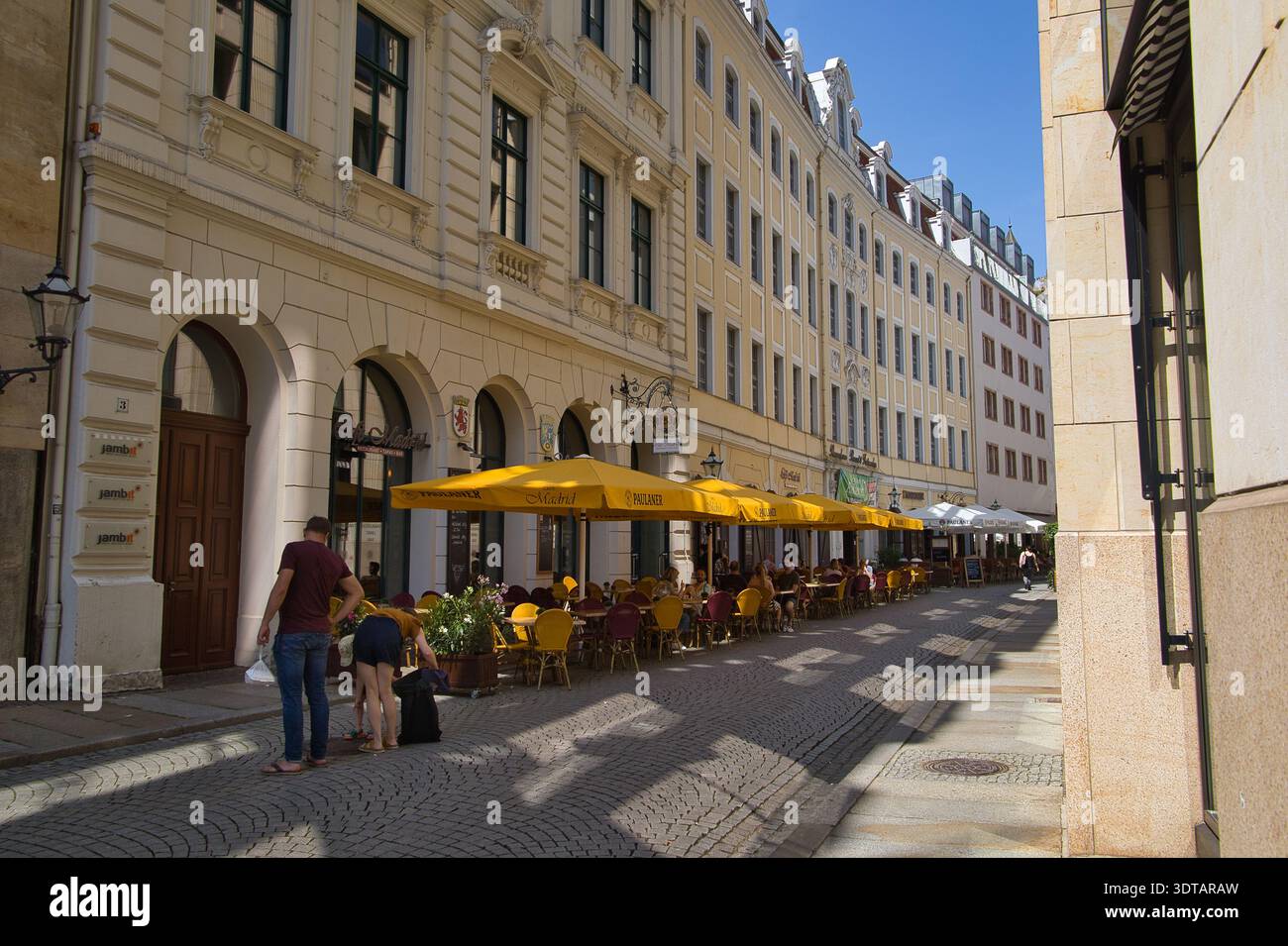 Vivace Klostergasse a Lipsia: Strada storica con invitanti aree pranzo all'aperto e prominenti ombrelloni gialli Foto Stock