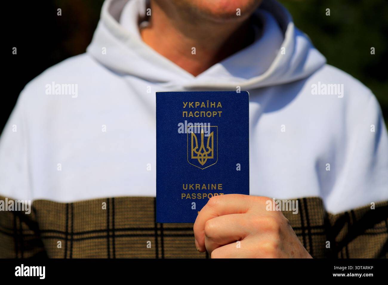 Un uomo ha un passaporto ucraino con un'iscrizione in ucraino - passaporto dell'Ucraina. Concetto di viaggio, rifugiato, turista, emigrante, mobilitazione, mig Foto Stock
