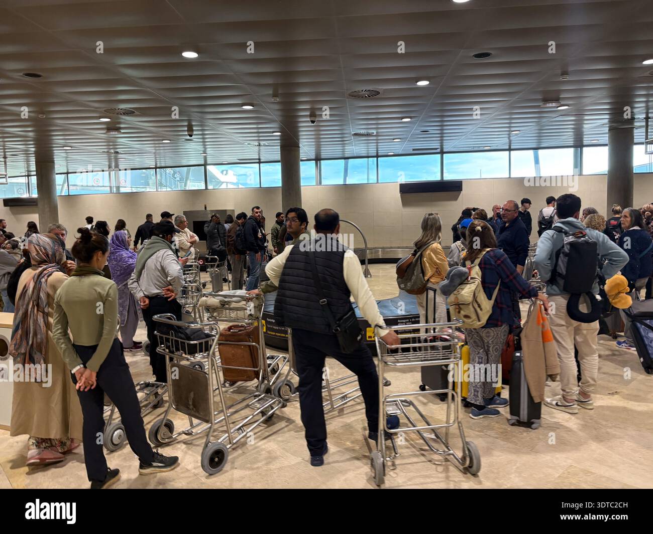 Area ritiro bagagli all'aeroporto di Valencia (Aeroport de València). Diversi viaggiatori si riuniscono intorno alle giostre dopo l'arrivo all'affollato viaggio spagnolo hu Foto Stock