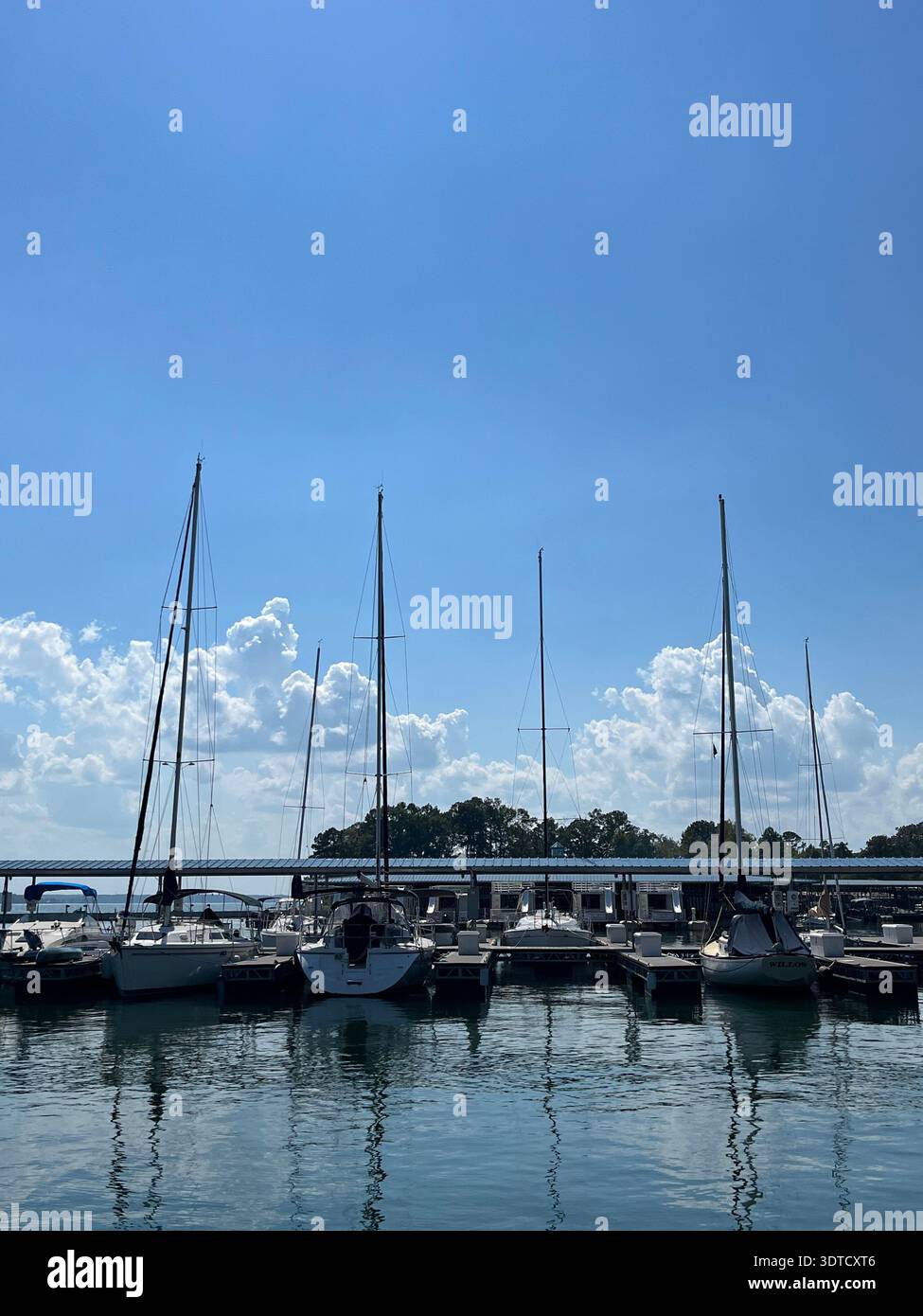 Le barche a vela sono ormeggiate in una bella giornata di sole. Il cielo blu domina mentre le nuvole si costruiscono all'orizzonte, portando probabilmente tempeste pomeridiane. Foto Stock