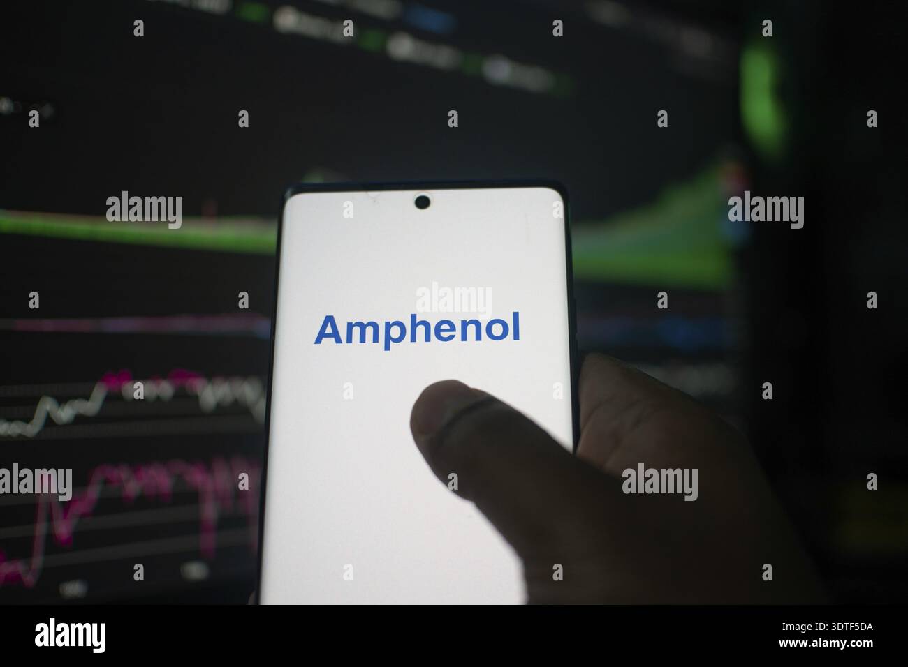 Un telefono con il logo Amphenol davanti alle tabelle della Borsa Foto Stock