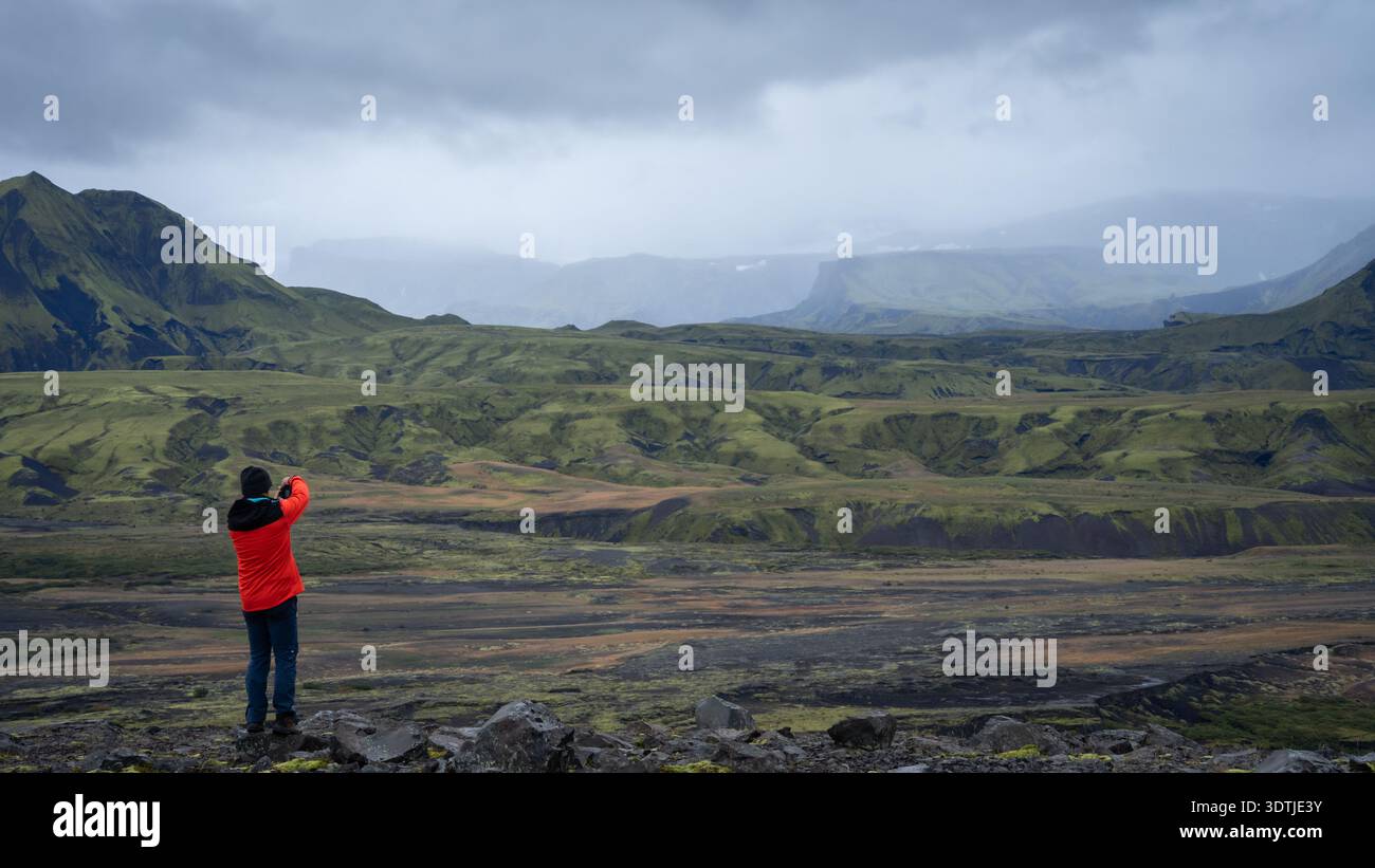 Uomo che fotografa l'aspro paesaggio islandese con nuvole di tempesta in avvicinamento, Highlands, Islanda Foto Stock