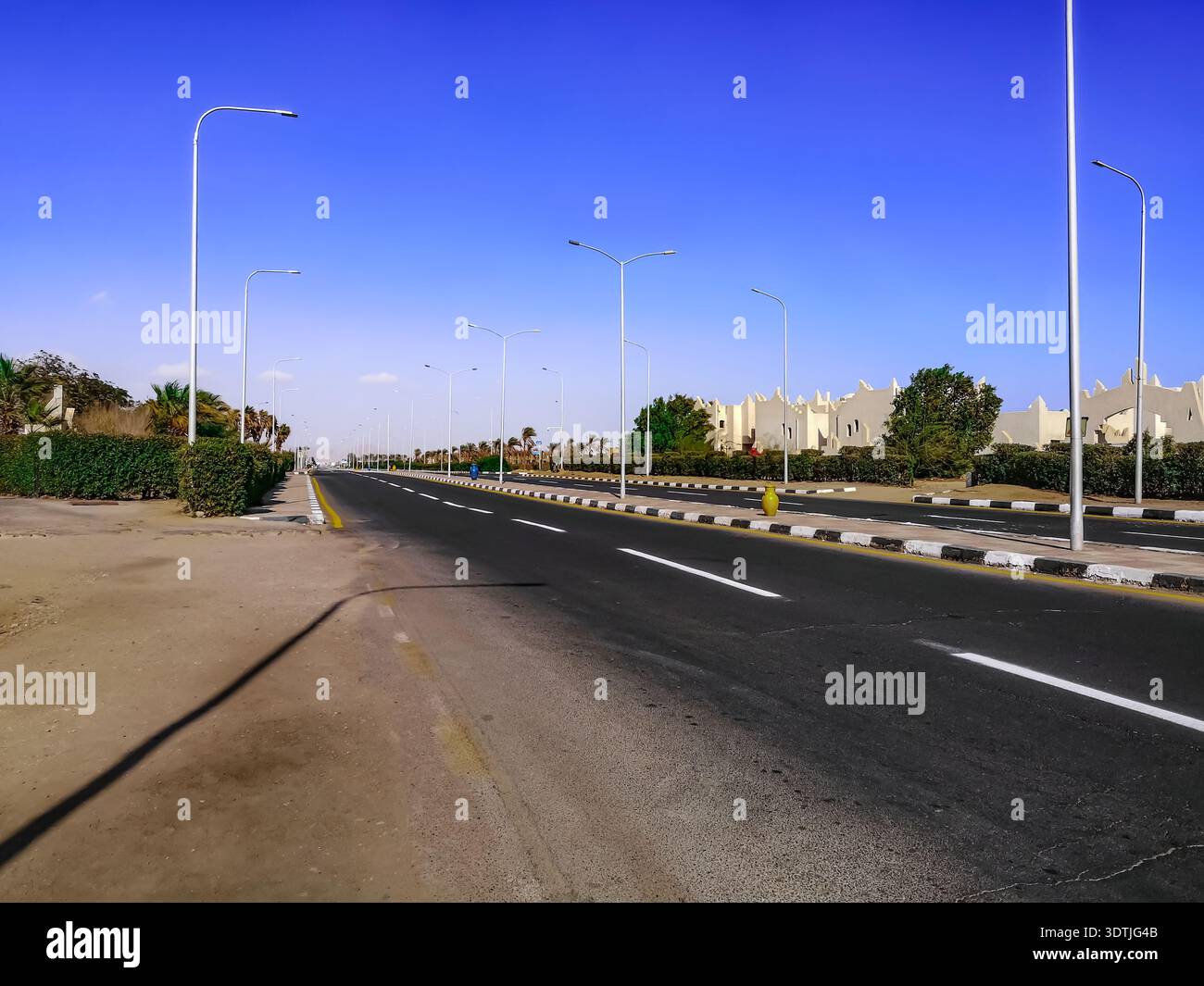 Strada vuota con grandi brocche sul marciapiede di Sharm El Sheikh (Egitto). Paesaggio urbano della città tropicale egiziana con strada deserta Foto Stock