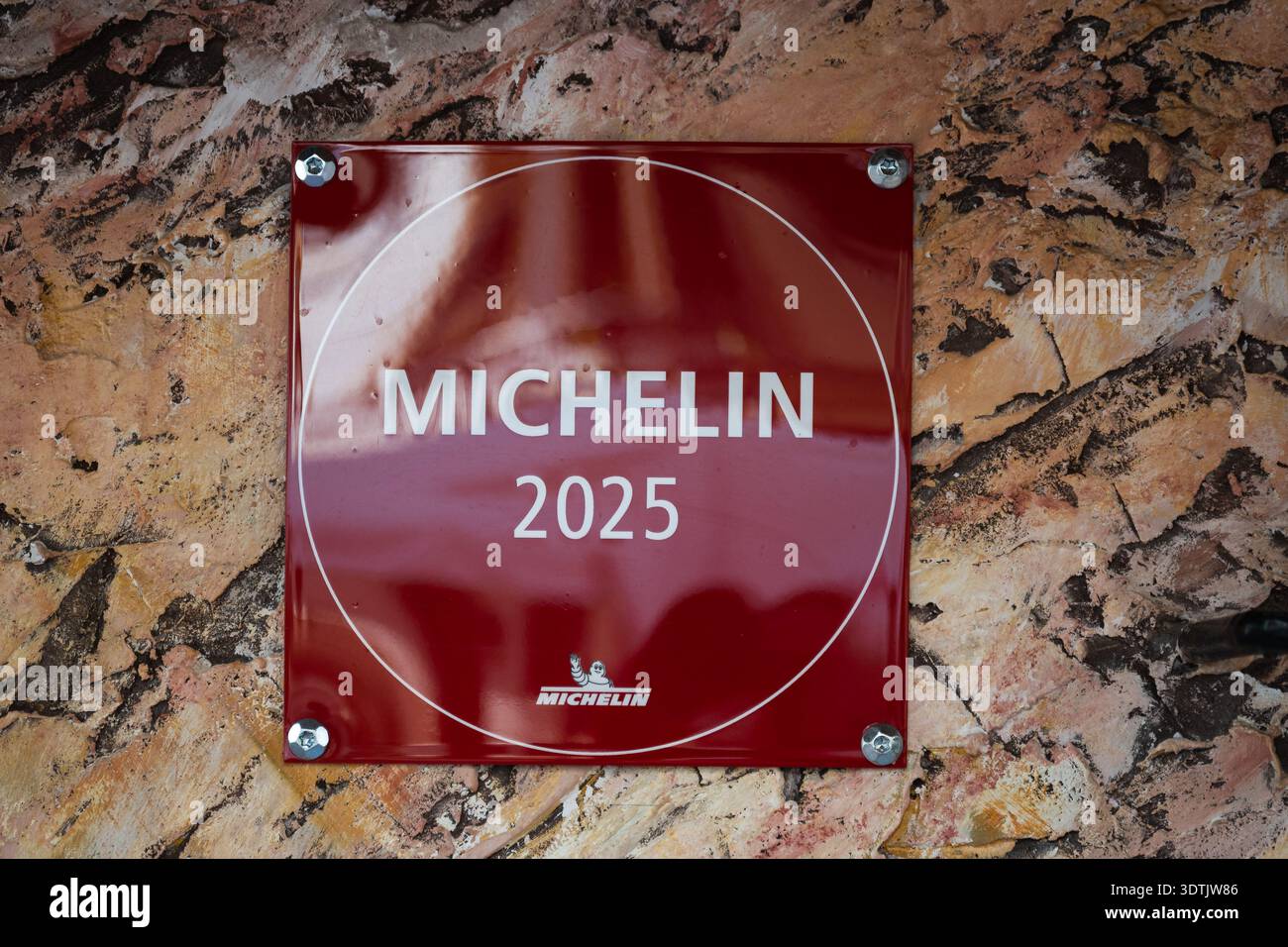 MIJAS, SPAGNA - 31 GENNAIO 2026 - Una prestigiosa targa Michelin 2025 rossa montata su un muro di pietra rustica all'ingresso di un ristorante di alta qualità. Foto Stock
