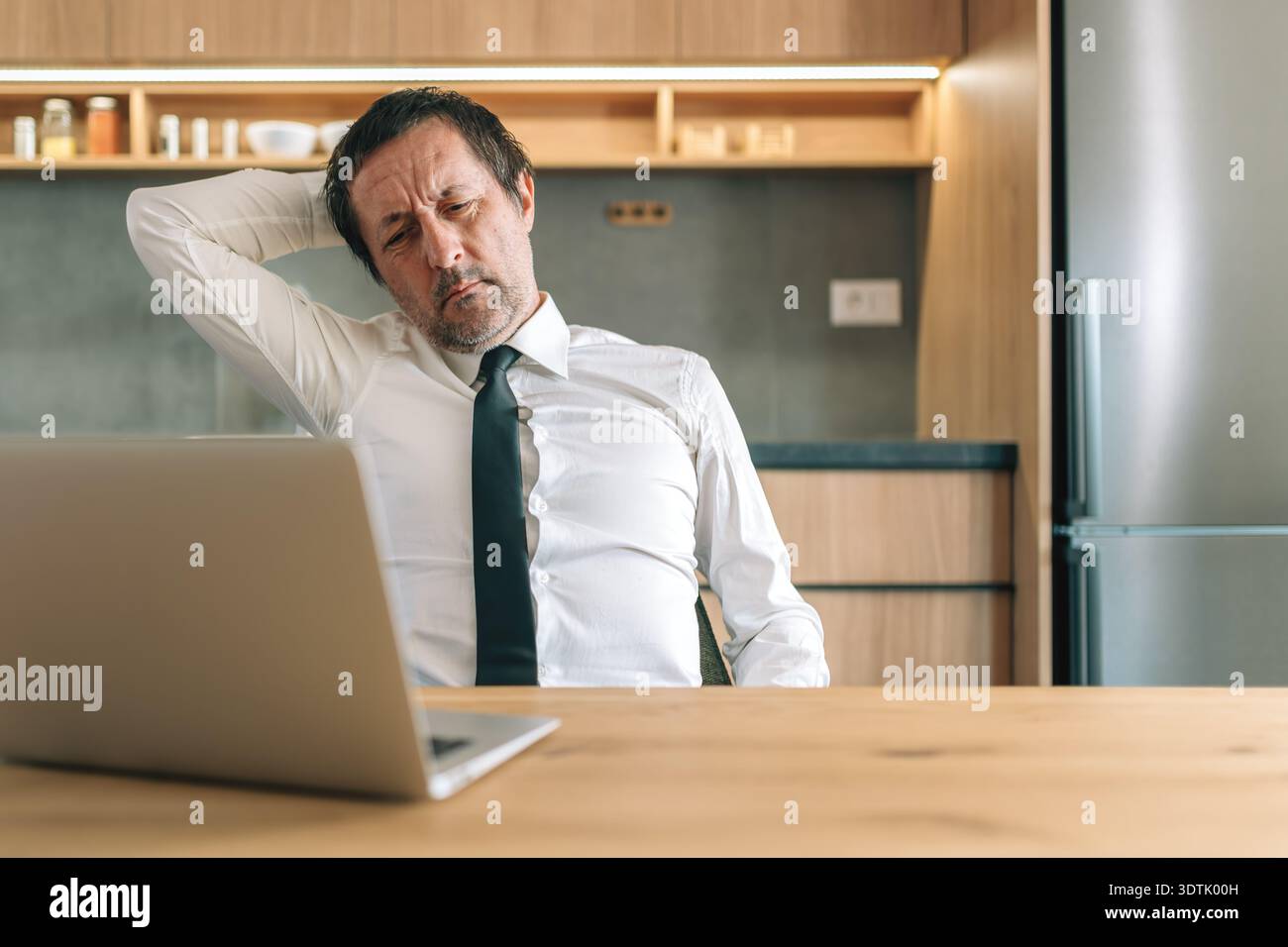 Uomo d'affari esausto che si piega di nuovo sulla sedia da ufficio stanco dopo il lavoro, attenzione selettiva Foto Stock