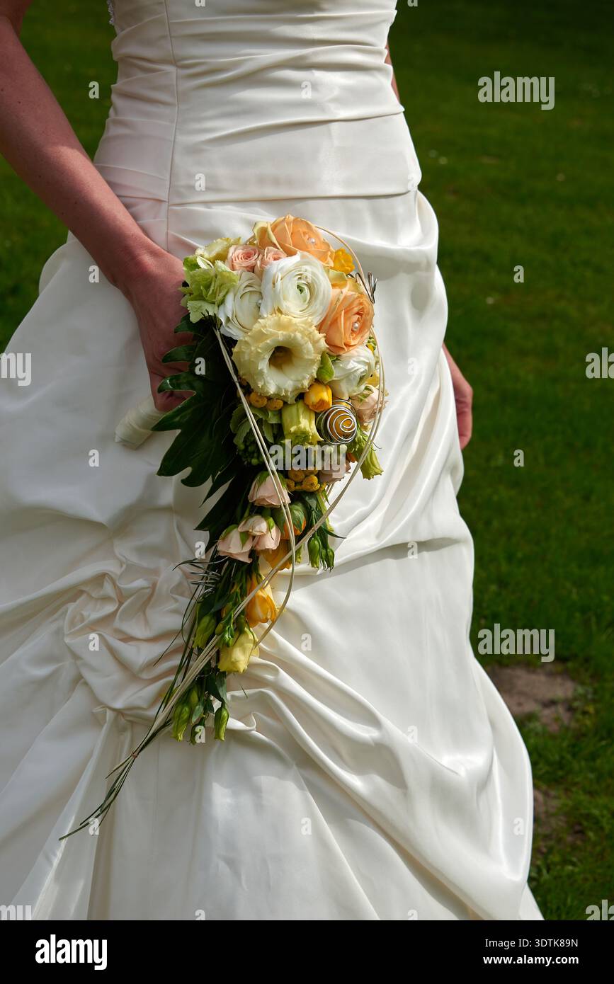 Uno scatto verticale ravvicinato che mostra una sposa in un abito da sposa bianco o avorio senza spalline, con un vivace bouquet a forma di goccia. Il bouquet Foto Stock