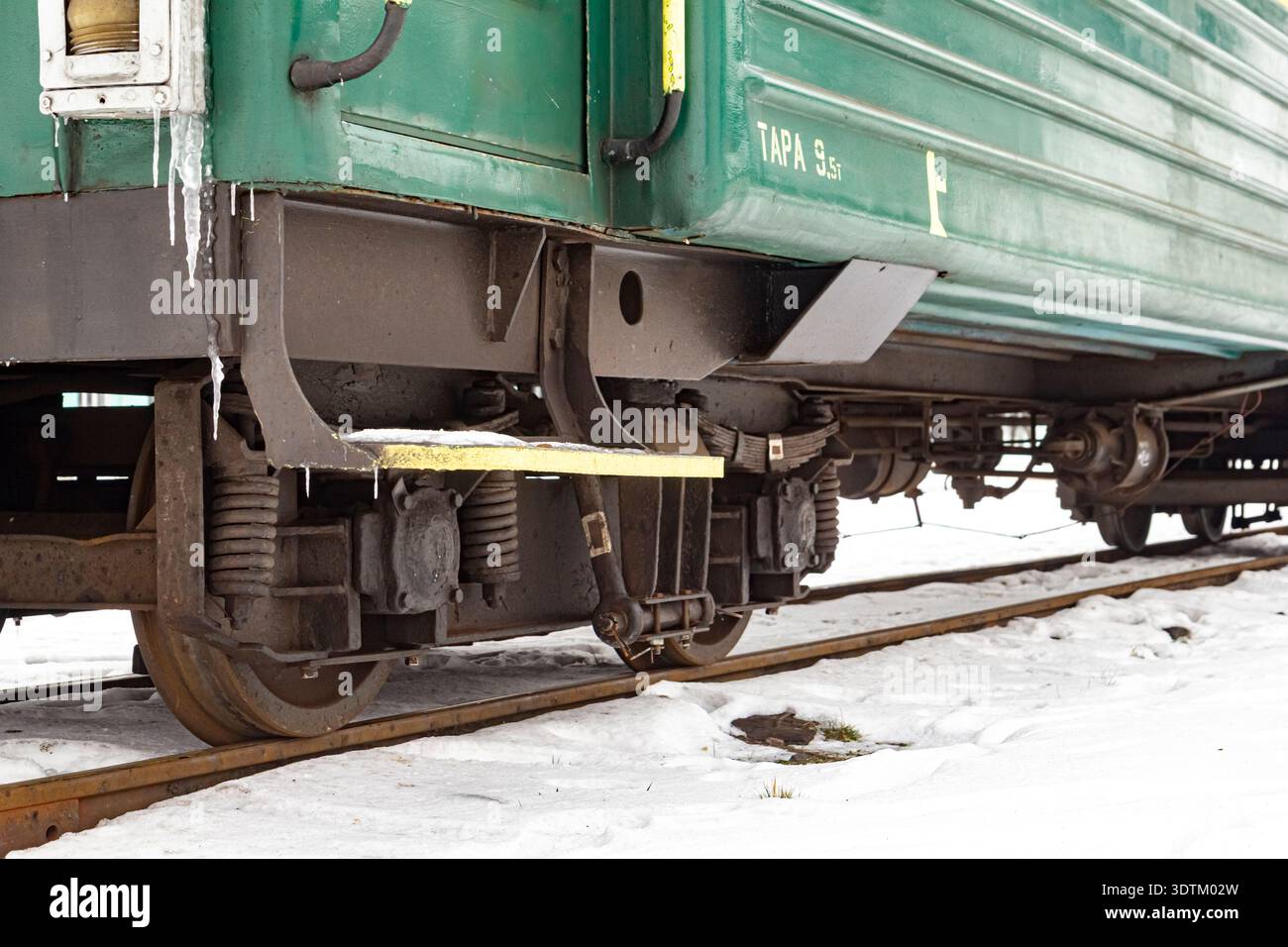 Vista ravvicinata delle ruote dei vagoni ferroviari e dello scalino di ingresso in metallo in inverno, che mostra dettagli, struttura industriale e atmosfera fredda stagionale Foto Stock
