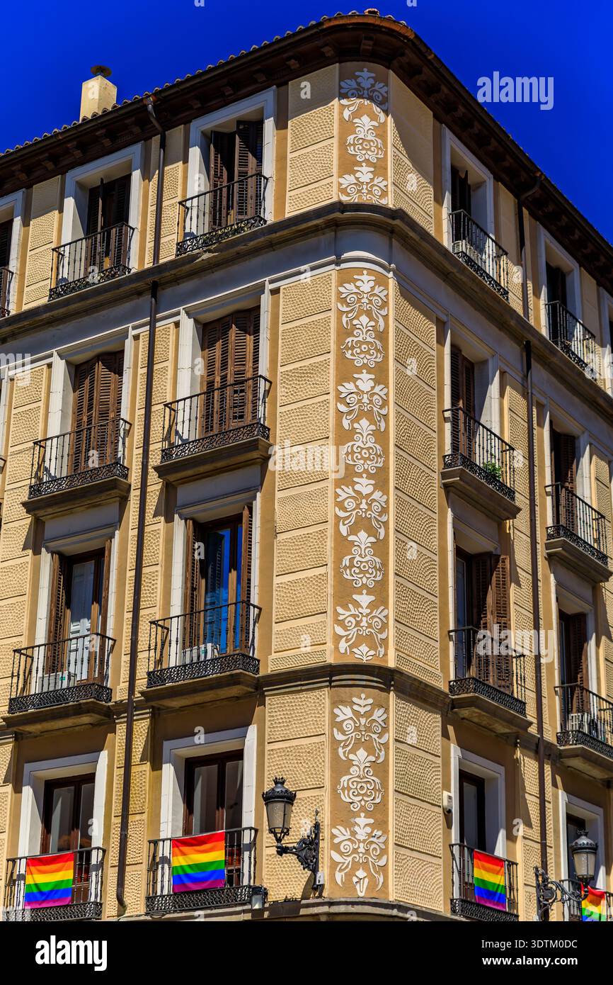 Splendidi edifici residenziali tradizionali con balconi ornati e pareti con intagli floreali decorati con bandiere arcobaleno LGBT Pride, Madrid, Spagna Foto Stock