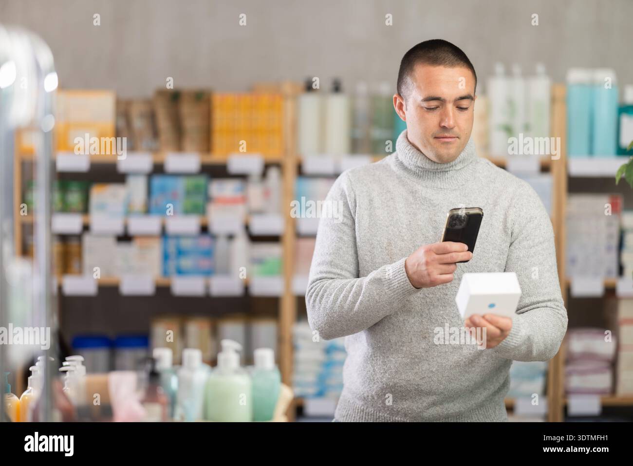 Man esegue la scansione del codice sulla confezione dell'unguento per controllare la data di scadenza Foto Stock
