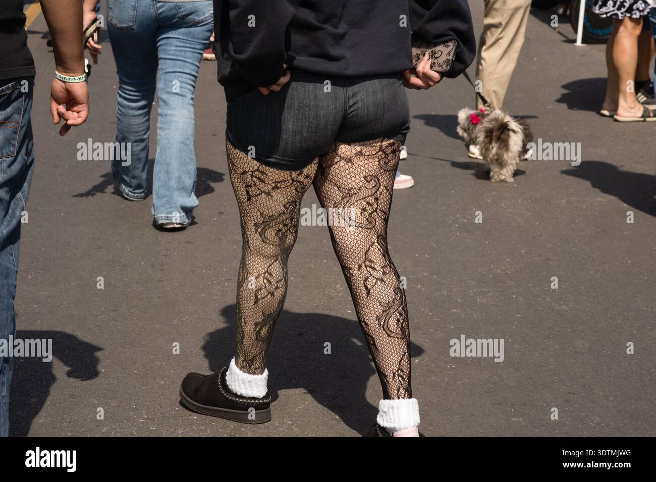 Le gambe di una donna vestita in modo informale con pantaloncini corti e calze a rete al Main Street Market di McAllen, Texas, USA. Foto Stock