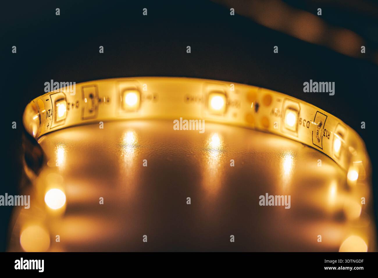 Primo piano macro con striscia luminosa a LED bianca calda che forma un moderno sfondo di illuminazione circolare Foto Stock