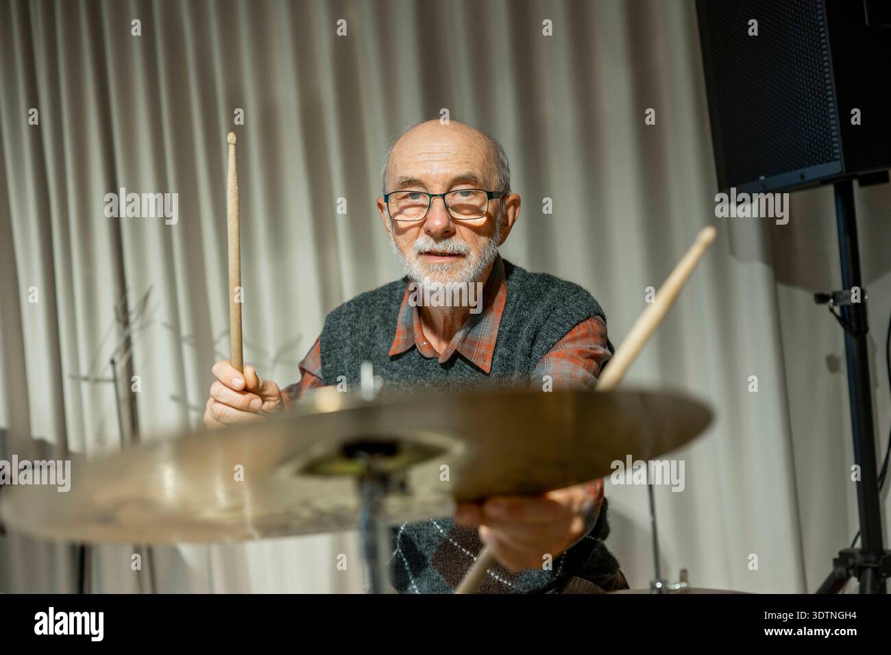 Uomo anziano che si diverte a suonare la batteria. Uomo anziano che si diverte a suonare la batteria. Musicista in pensione. modello rilasciato Foto Stock