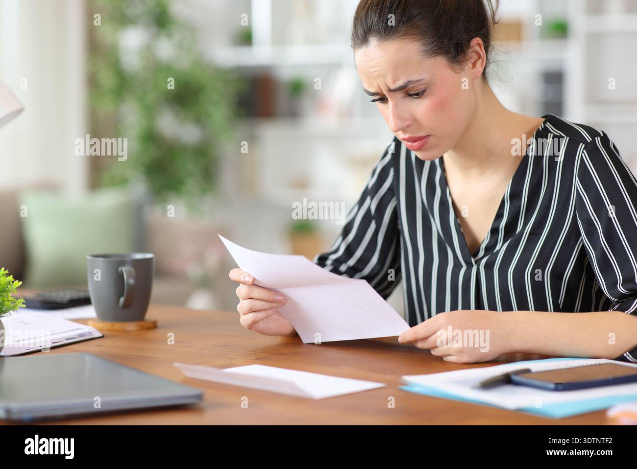 Lavoratore freelance preoccupato che leggeva documenti cartacei che lavorava a casa Foto Stock