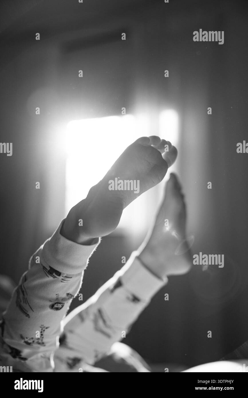 I piedi del bambino sono sollevati verso la finestra con la luce del mattino Foto Stock