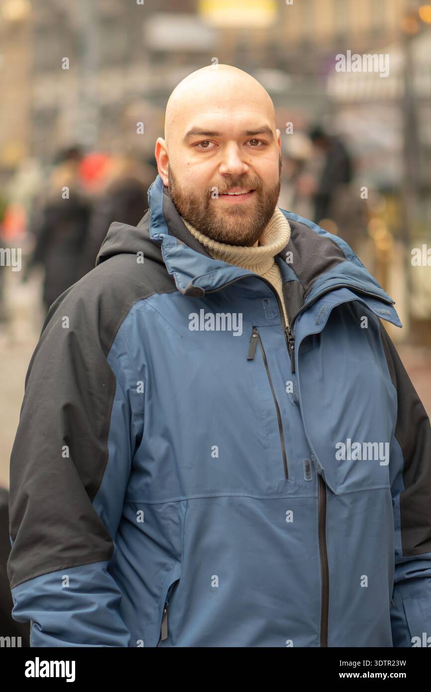 uomo di 35 anni in giacca invernale in piedi su una strada della città tra pedoni Foto Stock