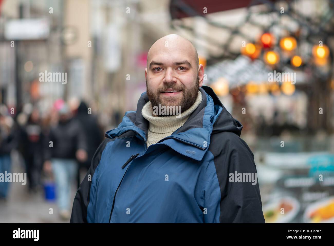 Uomo adulto in abiti invernali in posa nella zona pedonale della città in inverno Foto Stock