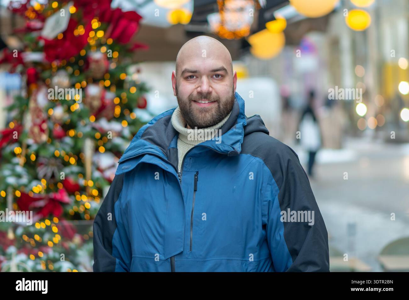Persona adulta con abbigliamento invernale sullo sfondo delle decorazioni natalizie della città Foto Stock
