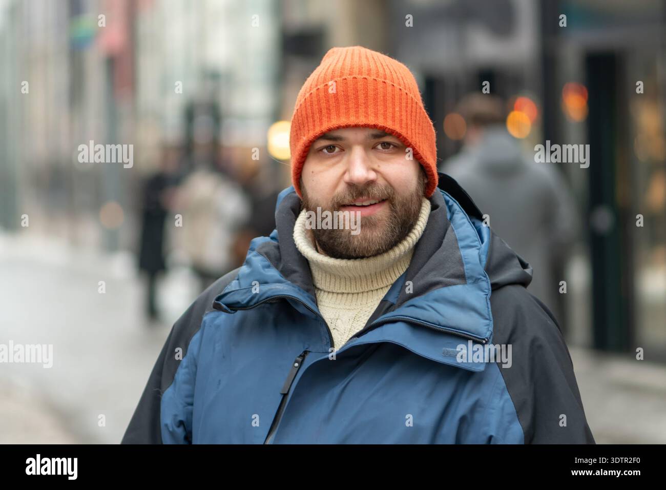 uomo di 35 anni che cammina lungo una strada della città in inverno con abiti caldi Foto Stock