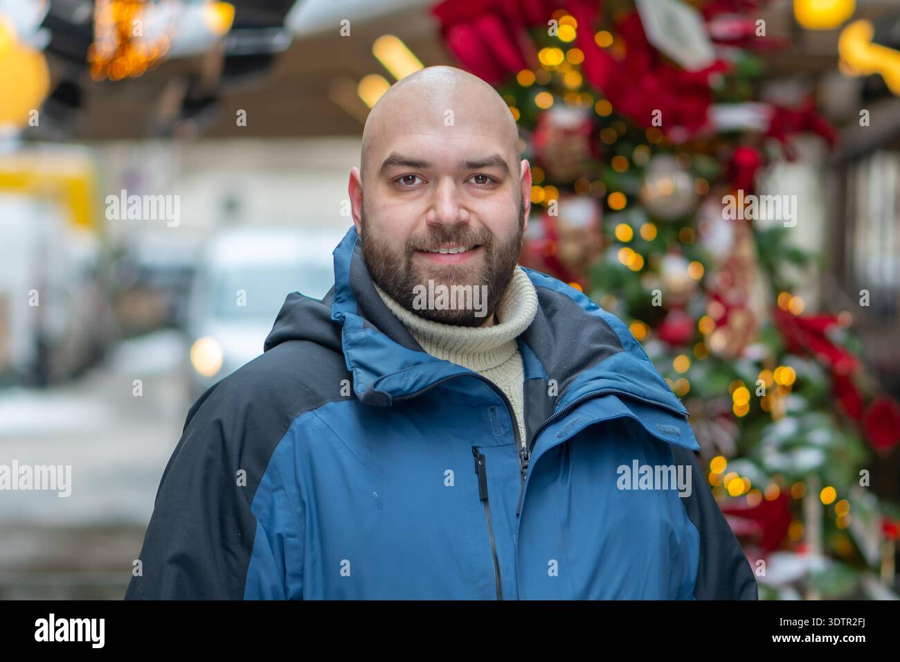 Uomo di 35 anni in una strada della città vicino all'albero di Natale decorato Foto Stock