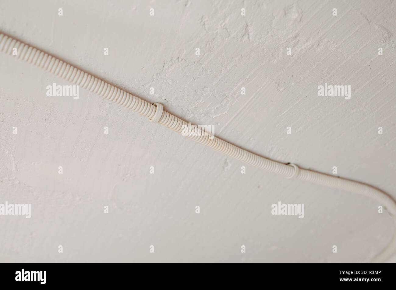 Installazione di tubi protettivi a soffitto fissata con dispositivi di fissaggio in metallo e finitura testurizzata per l'ispezione Foto Stock