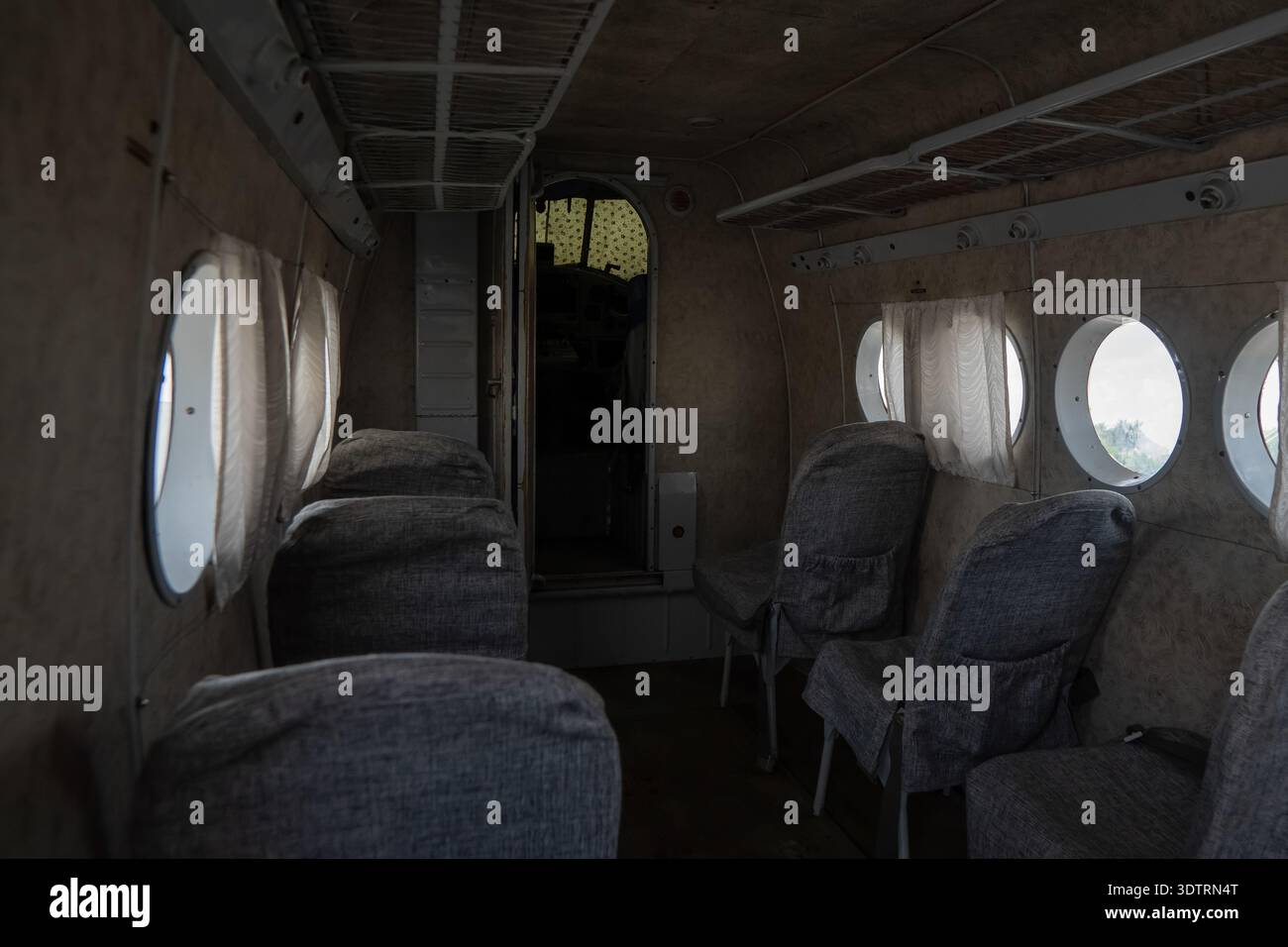 Interni di un velivolo d'epoca con sedili vuoti e illuminazione soffusa che creano un'atmosfera nostalgica per gli appassionati di aviazione Foto Stock