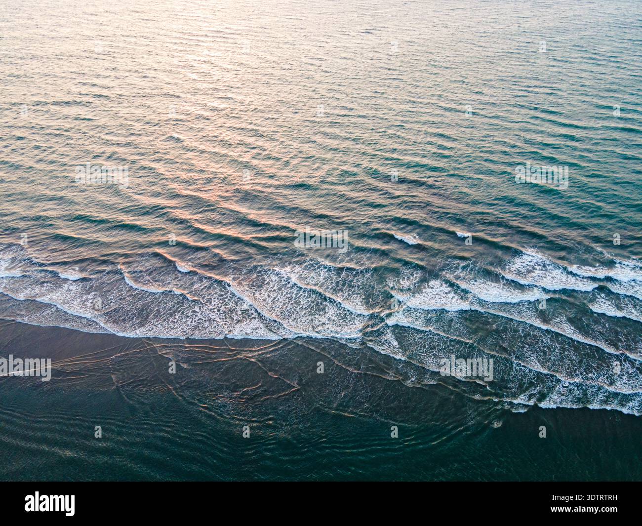 Vista aerea del mare che incontra la riva, le onde creano un motivo di pizzo bianco contro la sabbia scura, Cox's Bazar, Chittagong Division, Bangladesh. Foto Stock