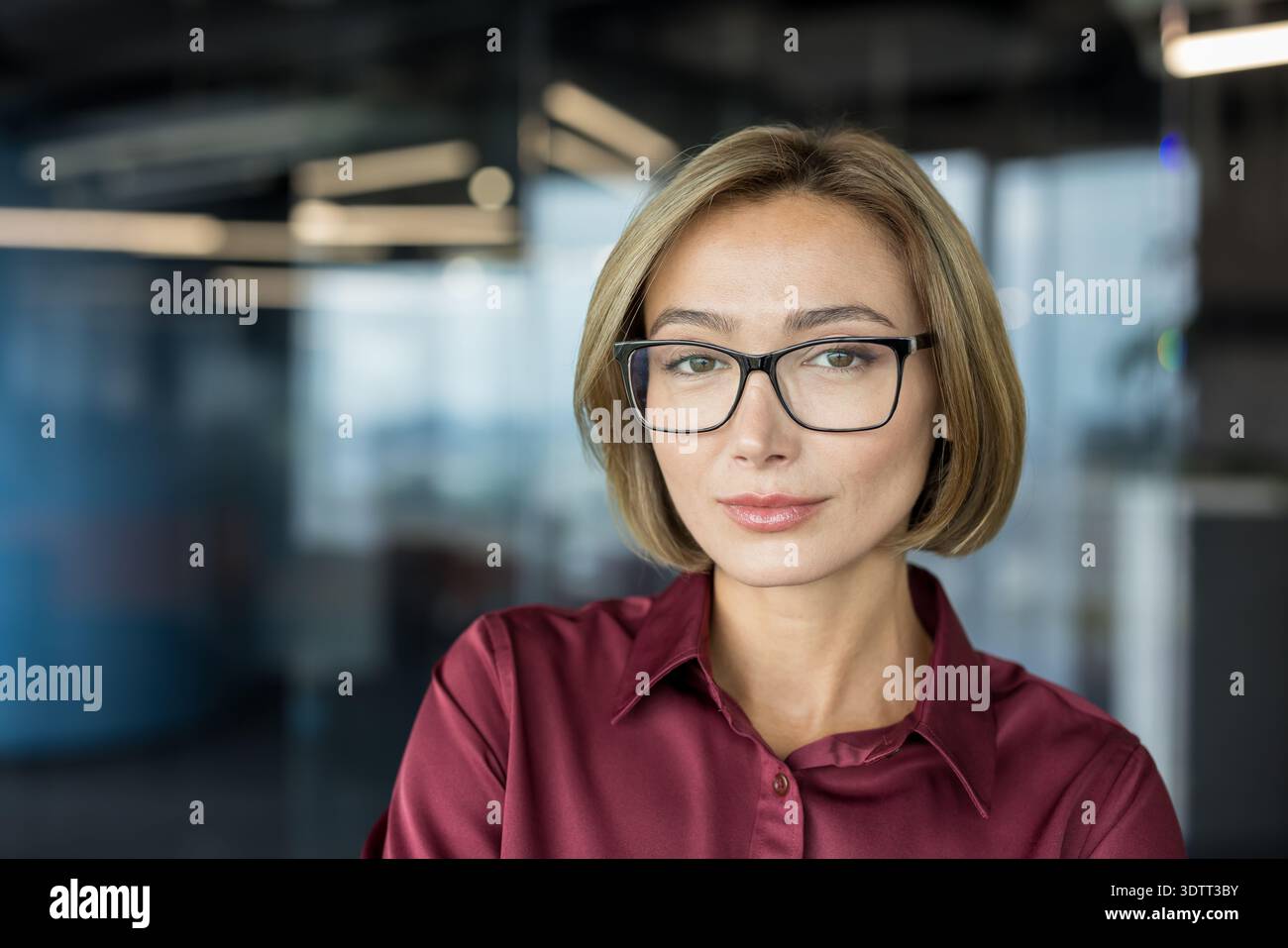 Donna d'affari sicura che indossa eleganti occhiali da vista e una camicia marrone, che ritrae professionalità e leadership mentre guarda la fotocamera in un cont Foto Stock