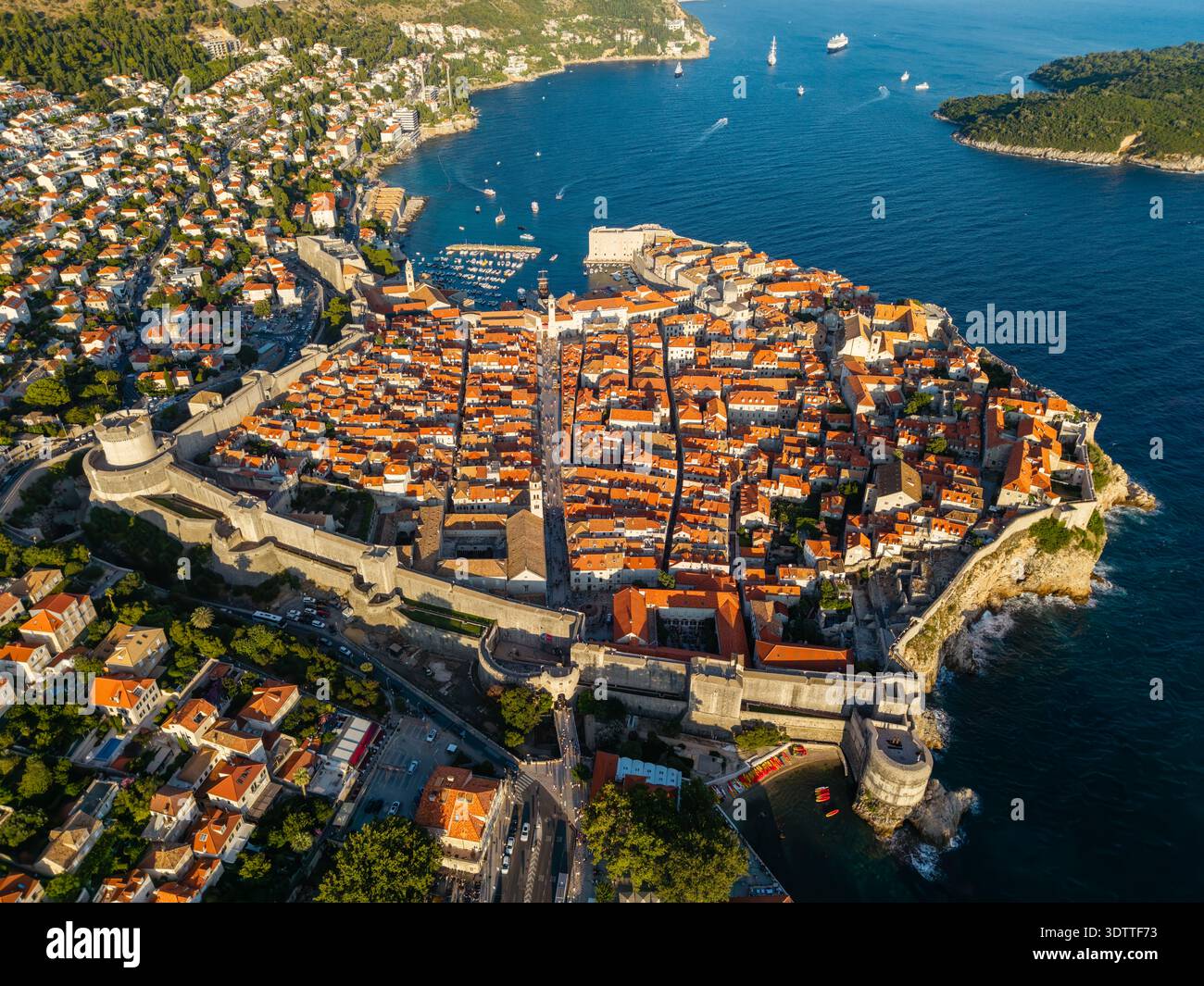 La vista aerea dei tetti in terracotta della città vecchia di Dubrovnik contrasta nettamente con il blu profondo del mare Adriatico, incorniciato da antiche mura di pietra, Dub Foto Stock