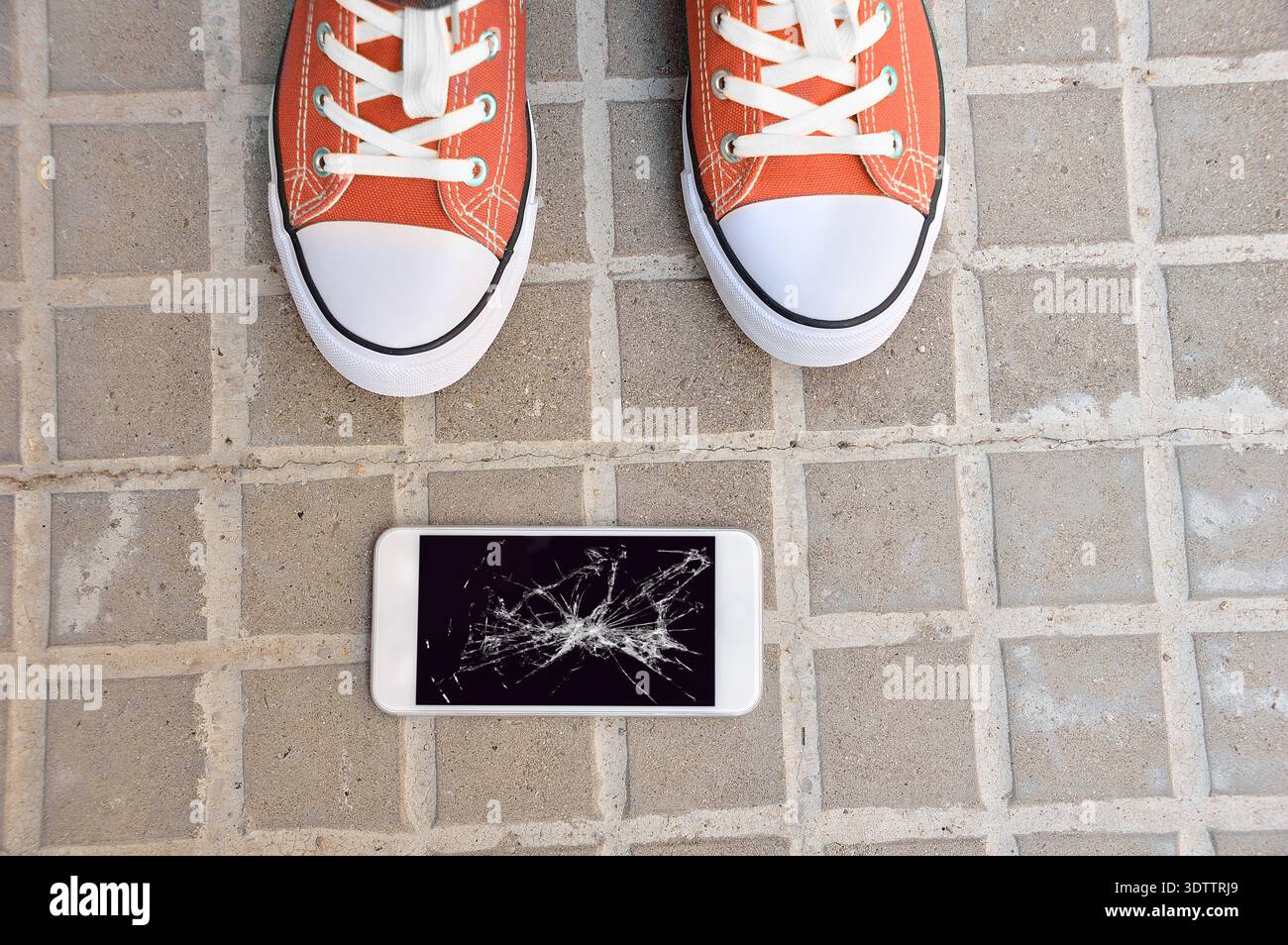Persona che sceglie uno smartphone rotto con uno schermo del terreno incrinato Foto Stock