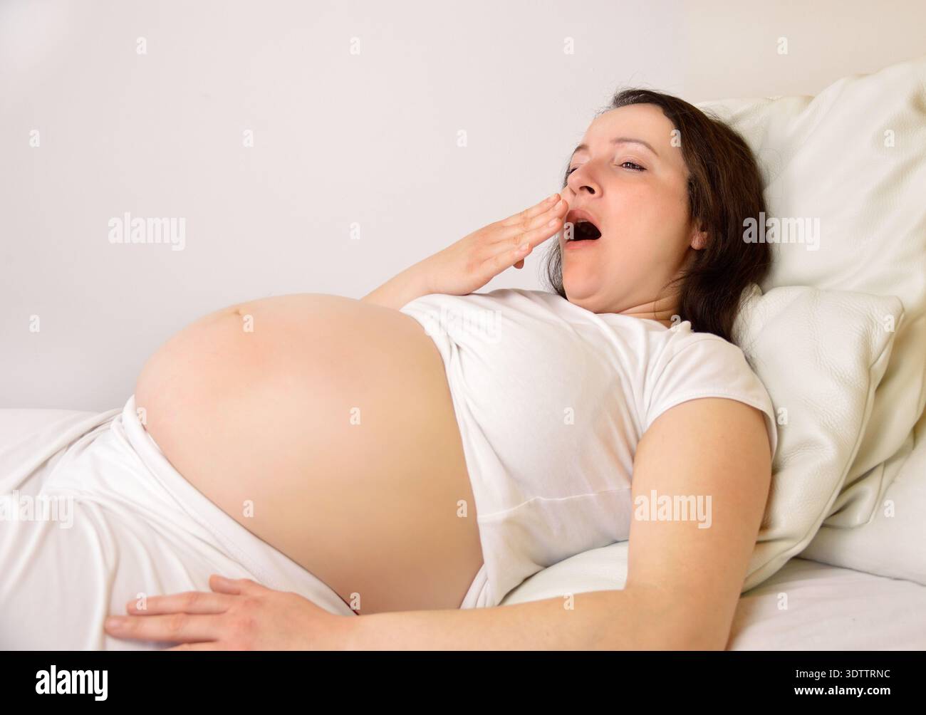 donna incinta che dorme sul suo letto a casa Foto Stock