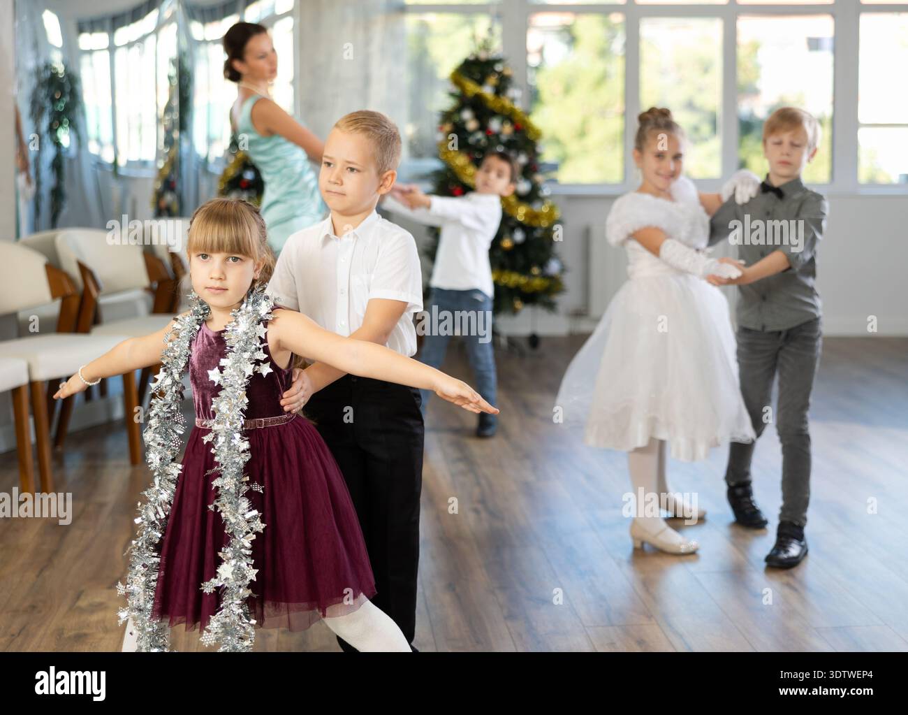 Bambini preadolescenti in abiti eleganti che praticano la danza di coppia nello studio natalizio Foto Stock