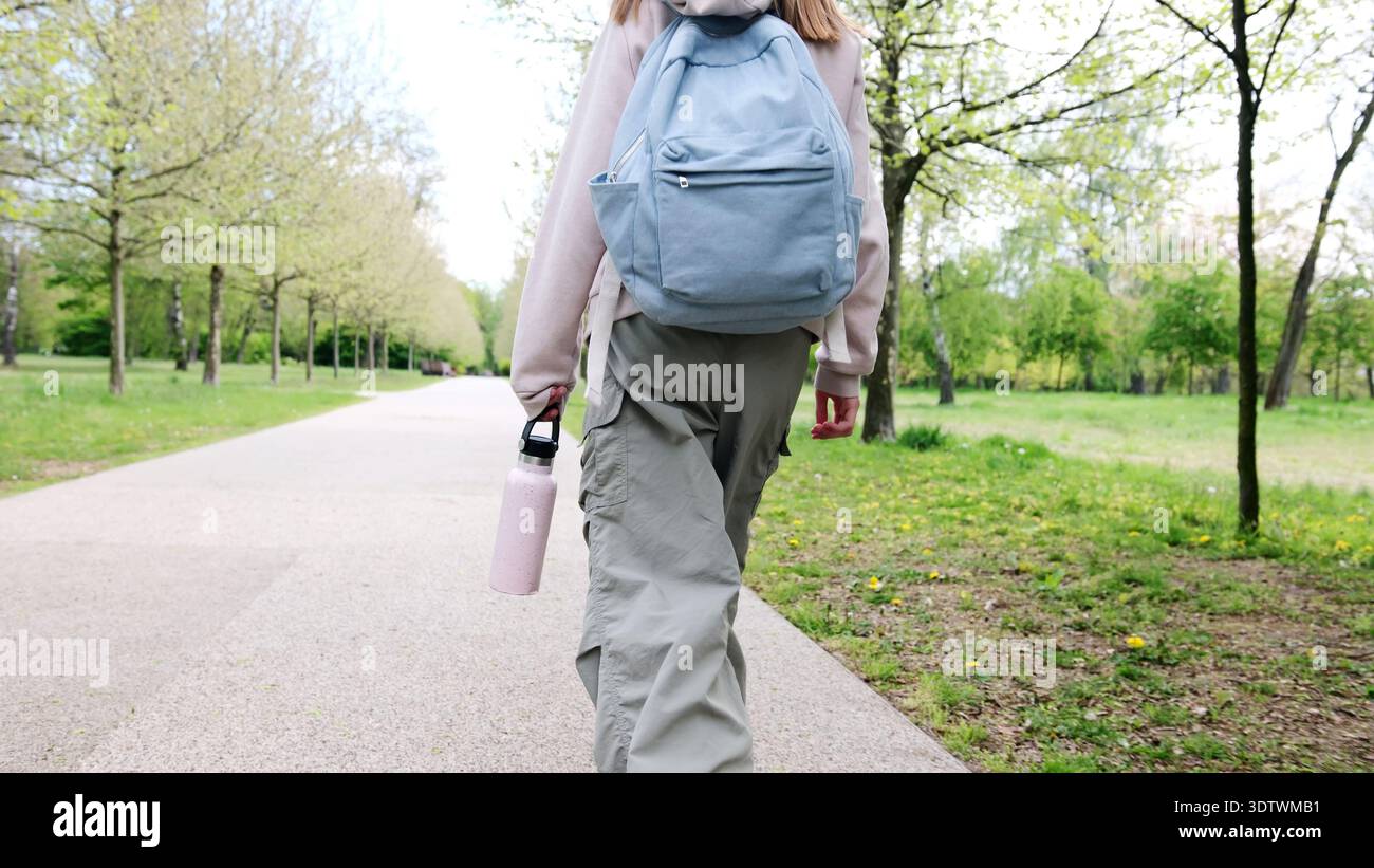 Ragazza con zaino che cammina a casa dalla scuola al parco Foto Stock