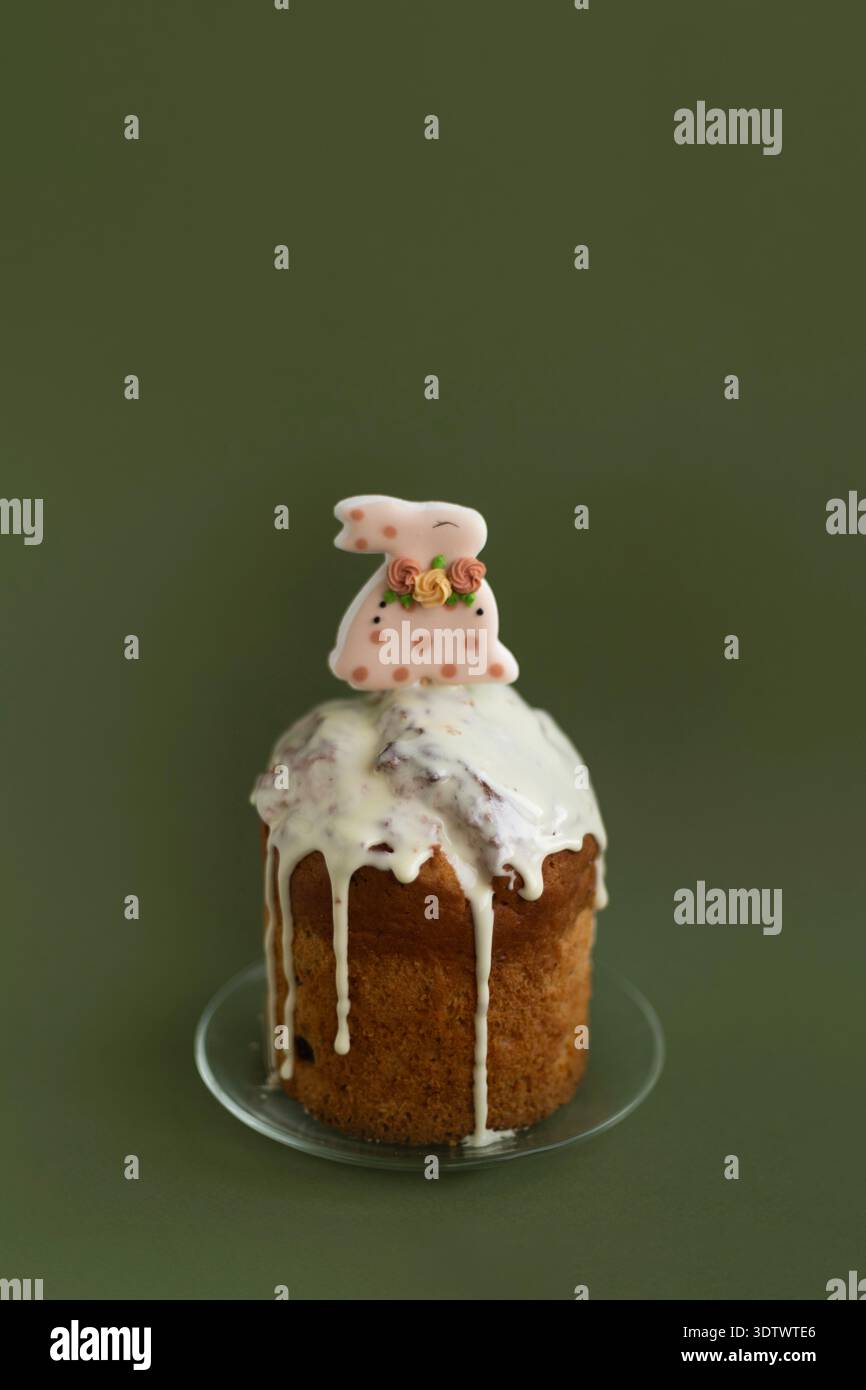 Torta pasquale per le feste con glassa liscia e bunny Topper su sfondo verde intenso, elegante composizione natalizia Foto Stock