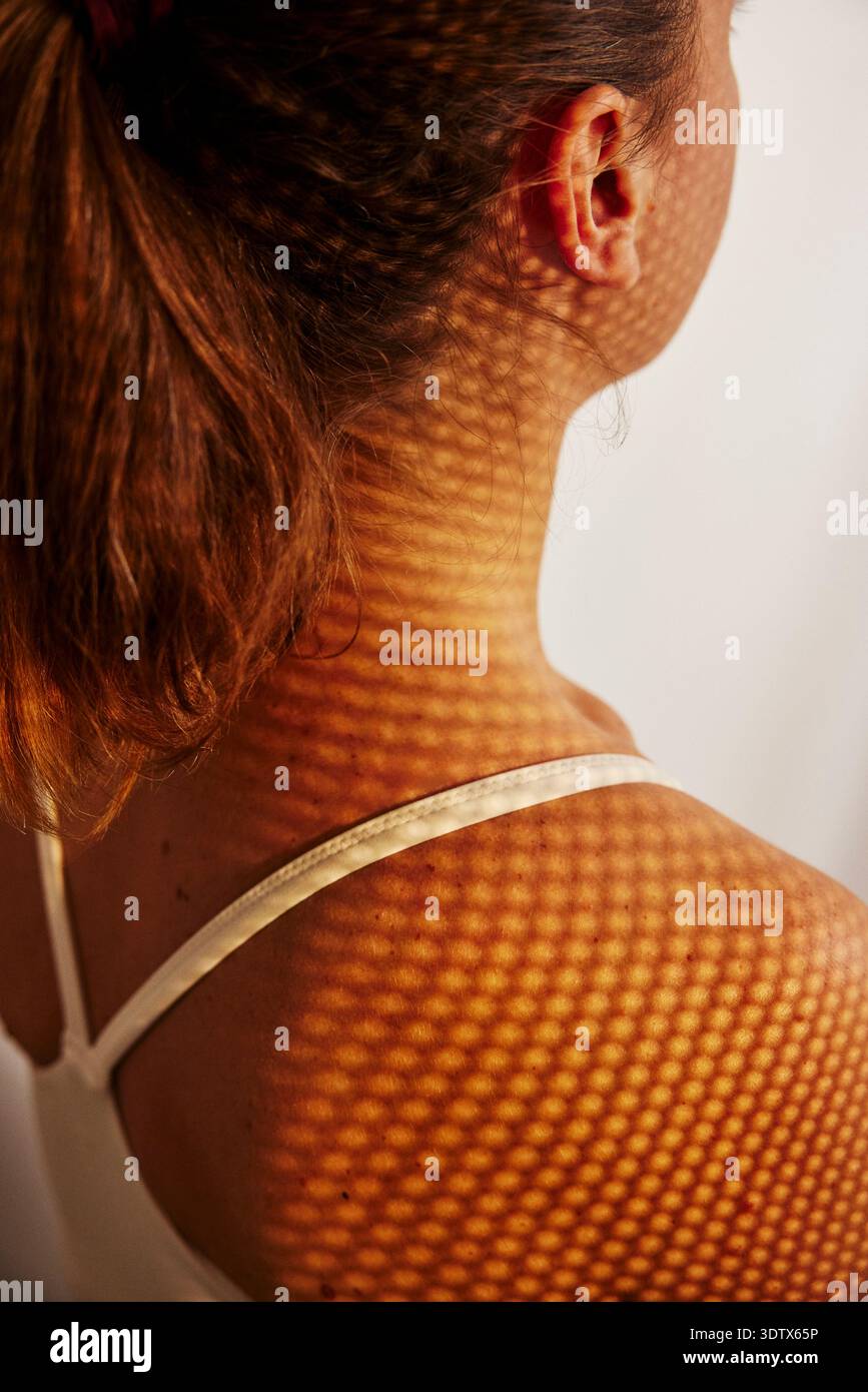 Vista ad angolo alto dell'ombra della luce solare modellata che cade sulla spalla della donna Foto Stock