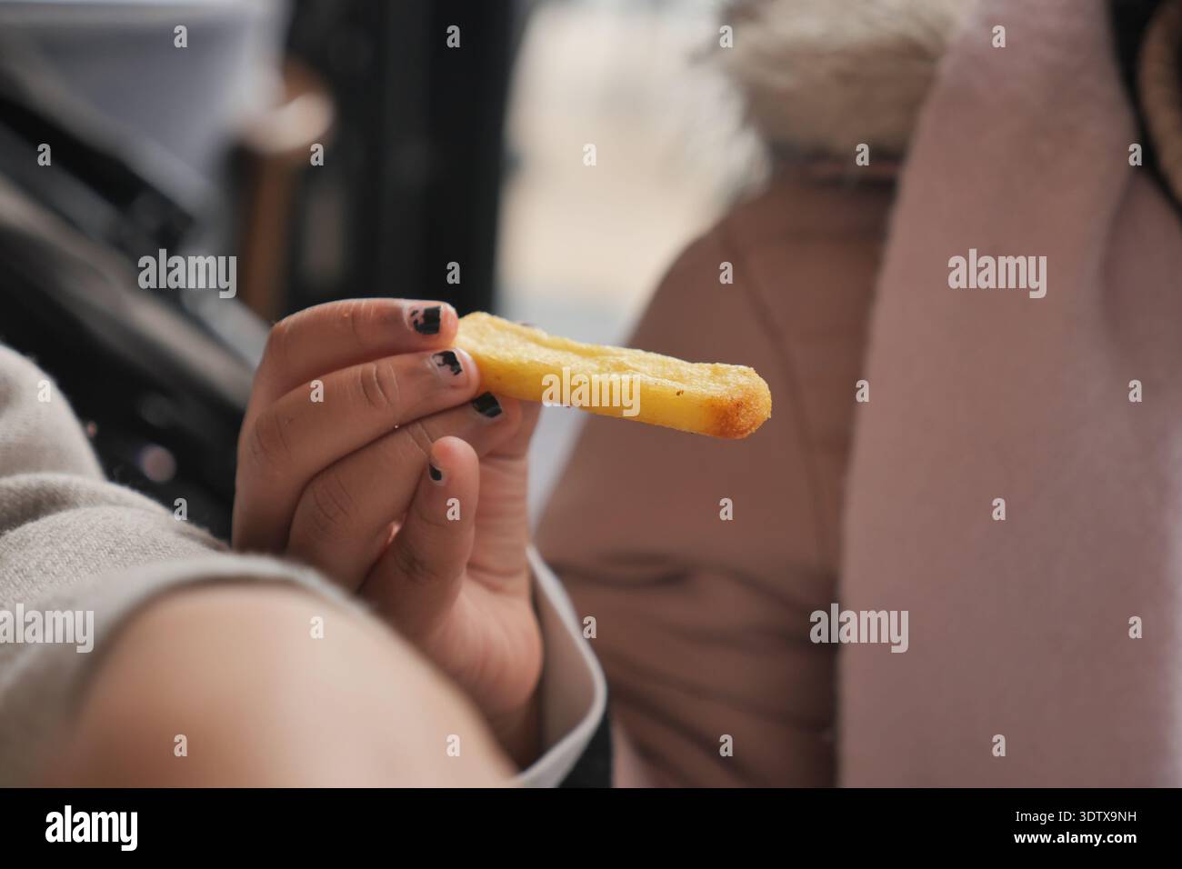 Bambino che tiene in mano Uno spuntino di frittura francese dorato che mostra la mano Foto Stock