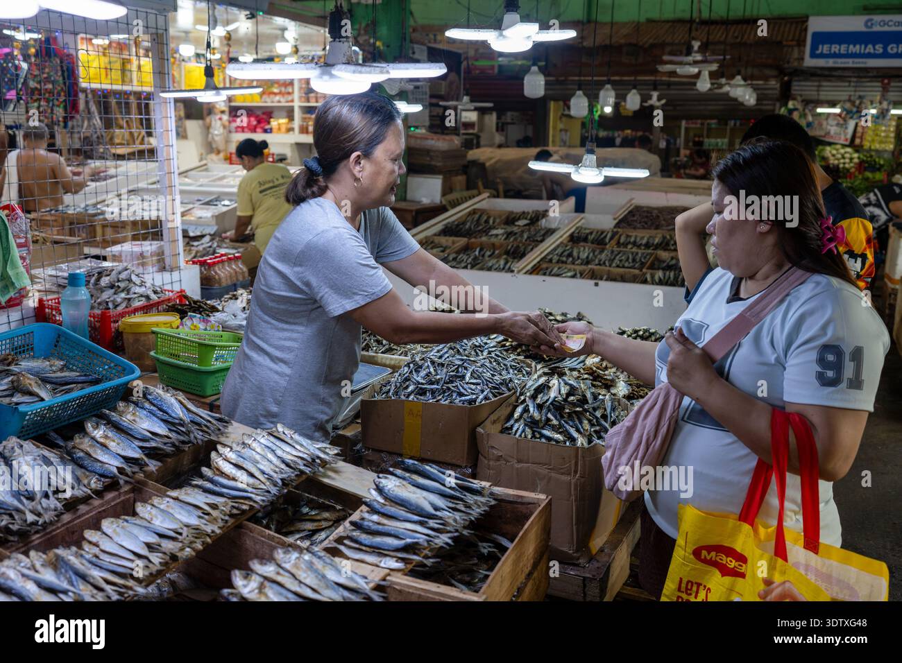 Il fornitore riceve il pagamento da un cliente mentre vende pesce essiccato al mercato pubblico Taboan di Cebu, Filippine, illustrando tutti i giorni i committenti locali Foto Stock