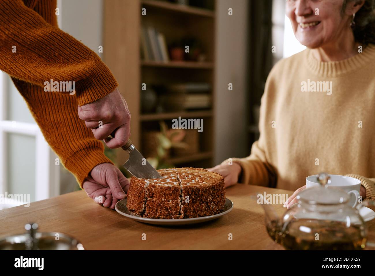 Donna caucasica anziana sorridente mentre l'uomo affetta torta Foto Stock