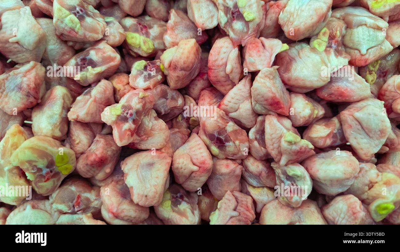 Una vista dall'alto verso il basso e ravvicinata che mostra una grande pila di code di pollo fresche e crude o nasi di parson, pronte per la cottura o la vendita in un mercato. Foto Stock