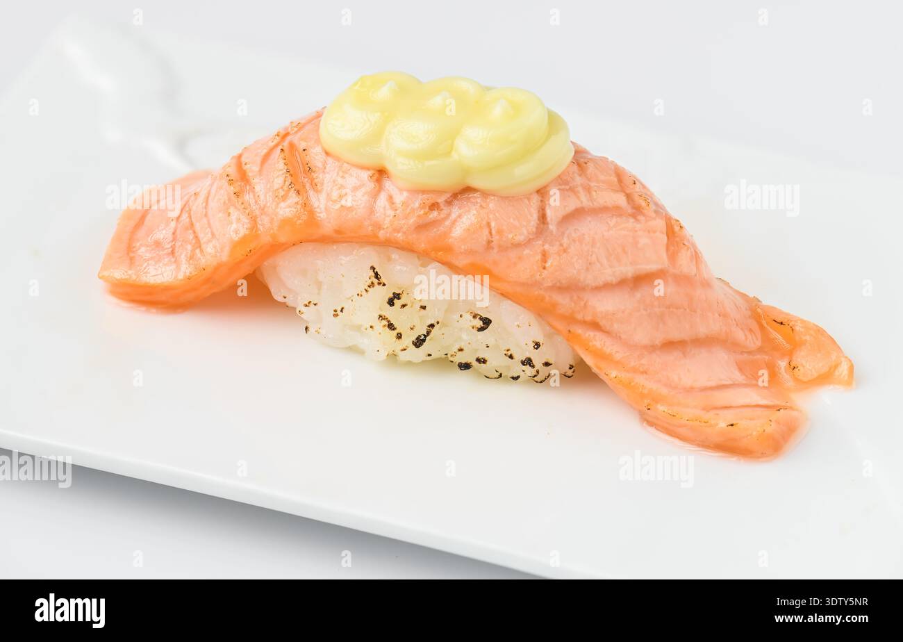 Sushi al nigiri di salmone grigliato condito con cremosa salsa di maionese, presentato splendidamente su un piatto bianco, combinando tradizionale e moderno giapponese Foto Stock