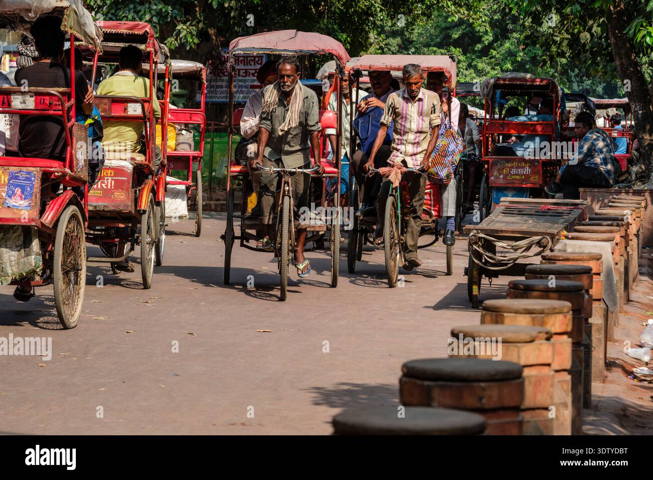 I risciò multipli trasportano i passeggeri lungo la strada alberata di Chandni Chowk, con più traffico in lontananza nella vecchia Delhi. Foto Stock