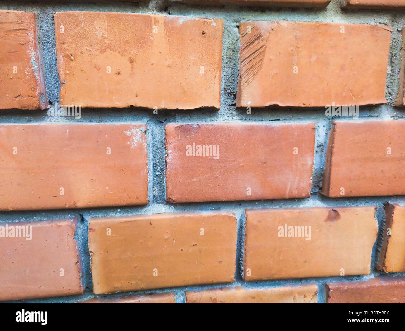 Una vista nitida e ravvicinata di un tradizionale muro di mattoni rossi a Ecseri út. La texture mette in risalto la superficie di argilla resistente agli agenti atmosferici e il robusto lavoro in muratura, perfec Foto Stock