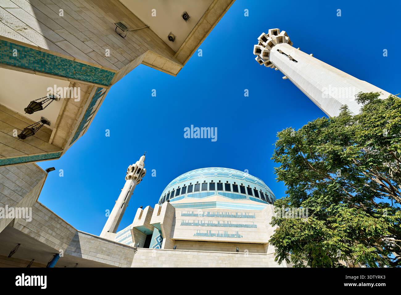 I visitatori guardano la moschea di Re Abd Allah ad Amman in Giordania sotto un cielo azzurro. La moschea presenta alti minareti e una grande cupola. Foto Stock
