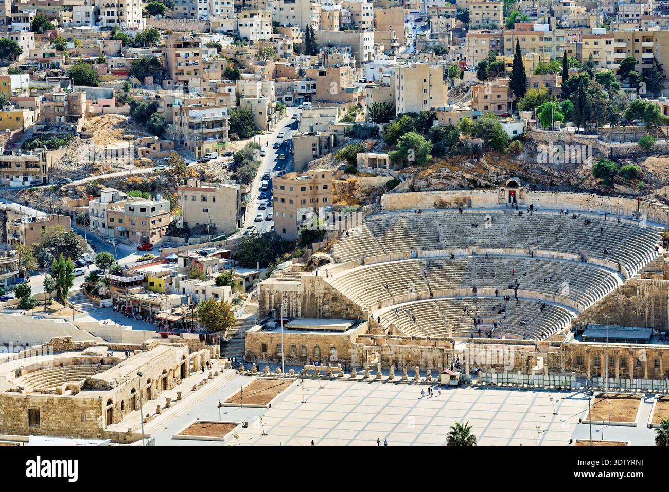 I visitatori esplorano il teatro romano di Amman, in Giordania. Il sito presenta antichi gradini in pietra e offre una vista della città moderna. Foto Stock