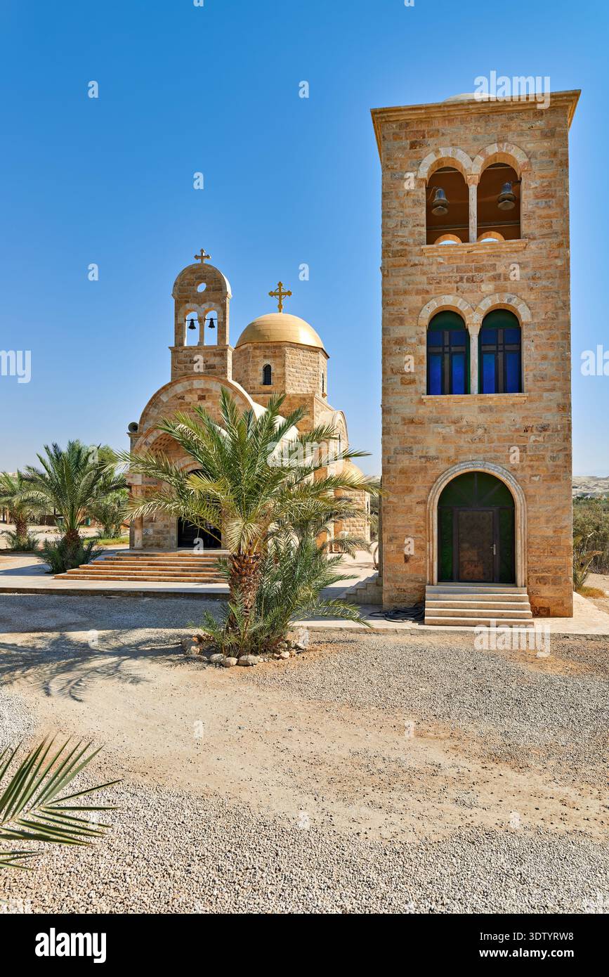 La chiesa di San Giovanni Battista si trova a Betania, oltre il Giordano. La chiesa ha una struttura in pietra e un'alta torre. Le palme circondano l'area. Foto Stock