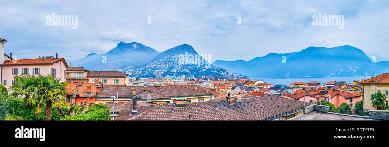 vista panoramica delle montagne dietro i tetti storici urbani di Lugano, Svizzera Foto Stock
