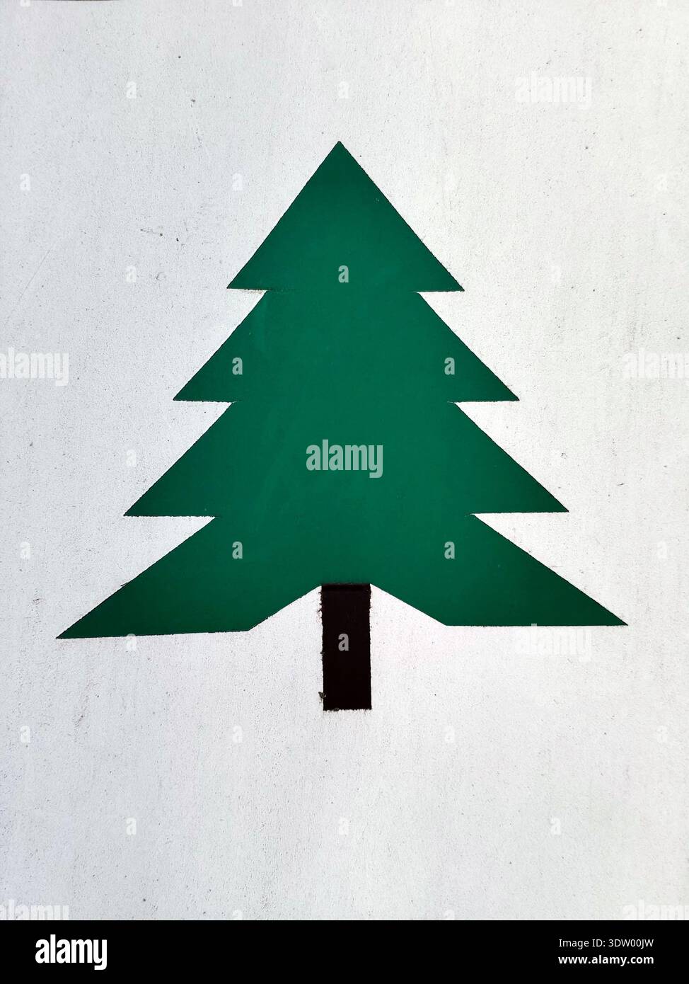 Simbolo di albero geometrico verde dipinto su una parete bianca. Forma piatta con sezioni triangolari e tronco nero, struttura visibile delle pareti, piccole crepe, graffi Foto Stock
